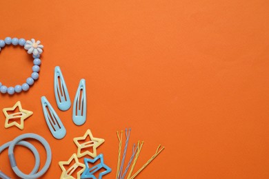 Photo of Cute hair accessories on orange background, flat lay. Space for text