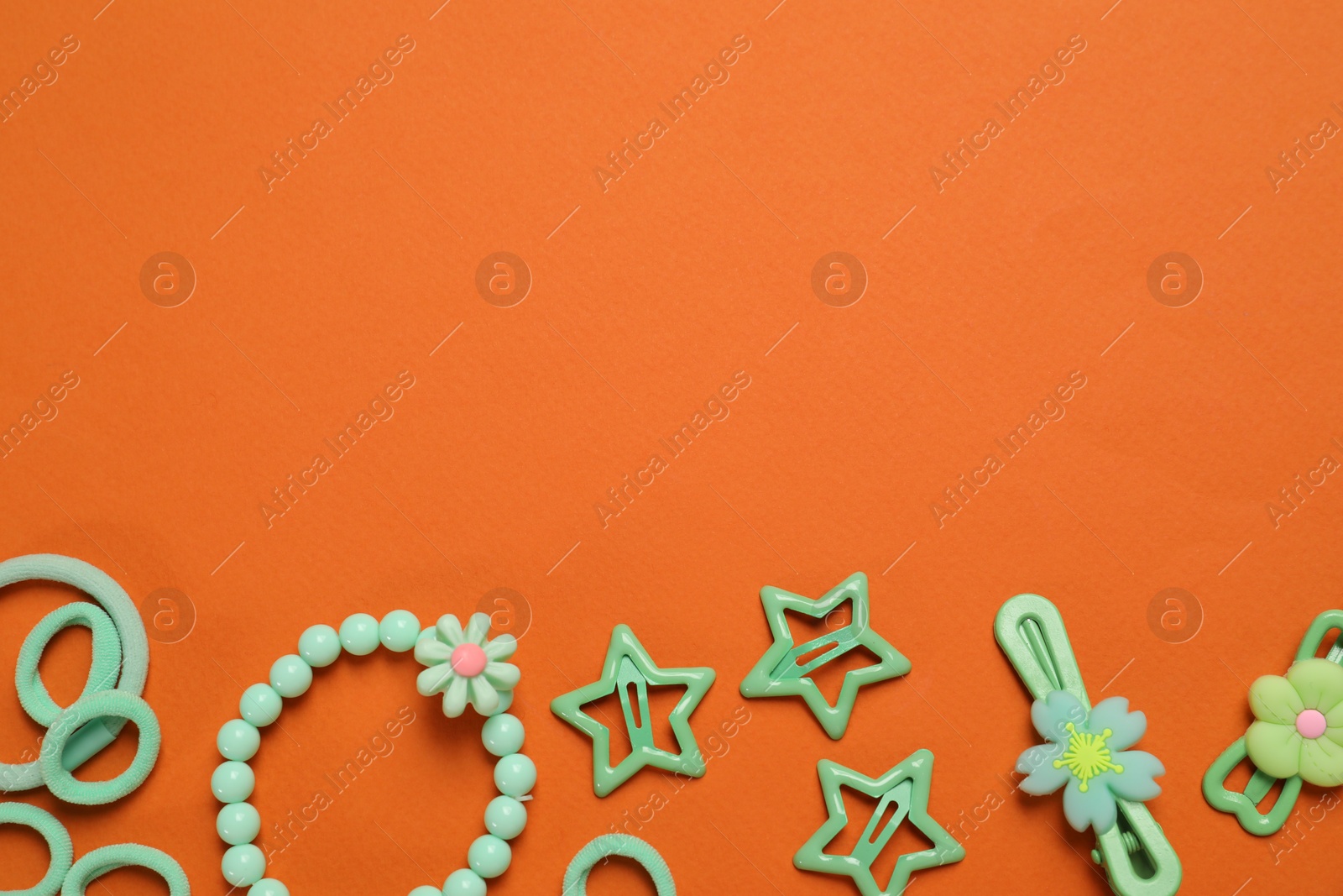 Photo of Cute hair accessories on orange background, flat lay. Space for text