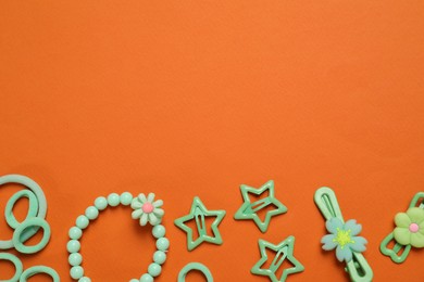 Photo of Cute hair accessories on orange background, flat lay. Space for text