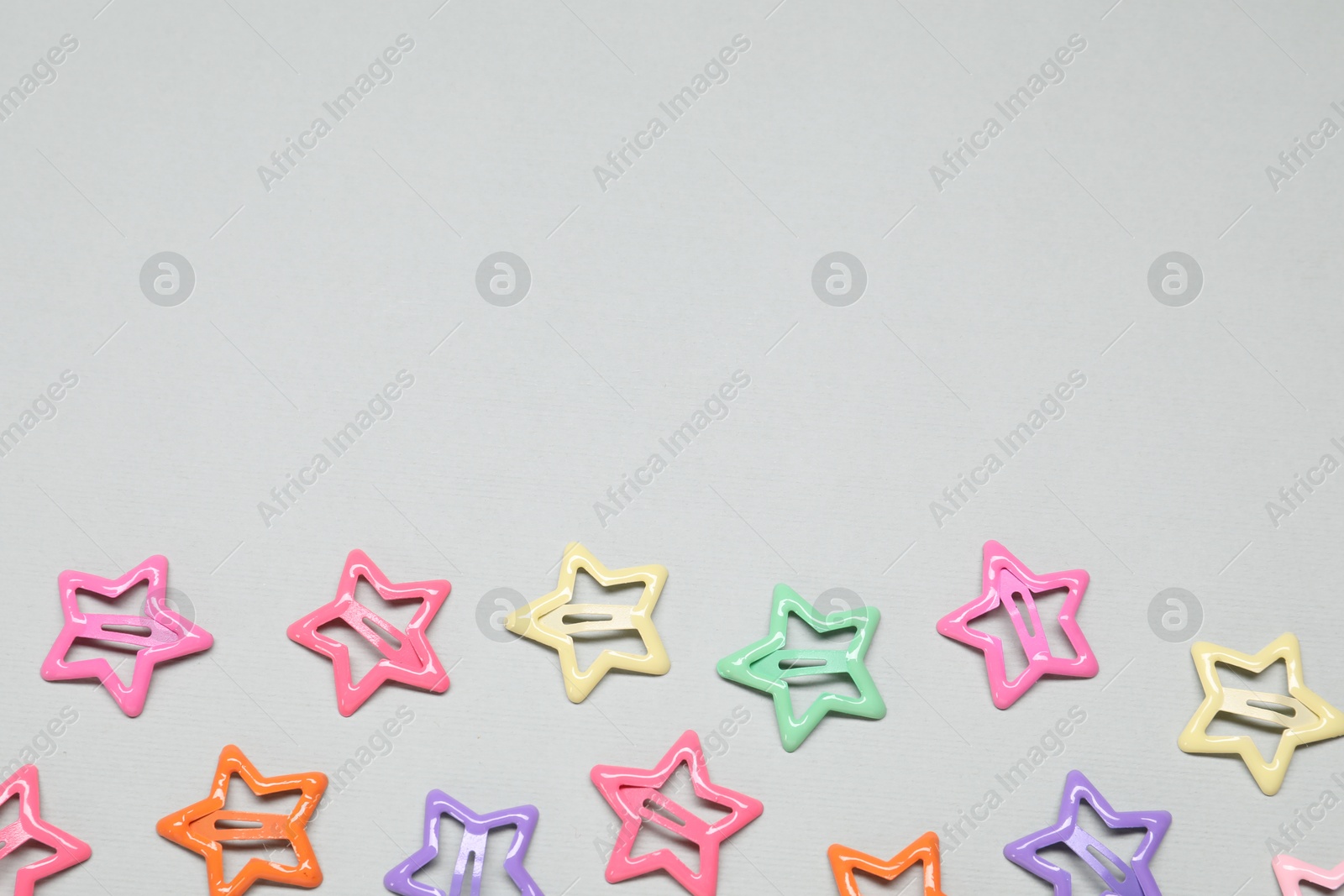 Photo of Colorful star shaped hair clips on light grey background, flat lay. Space for text