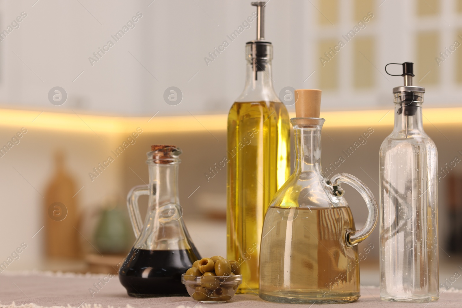 Photo of Bottles of salad dressings and olives on table in kitchen