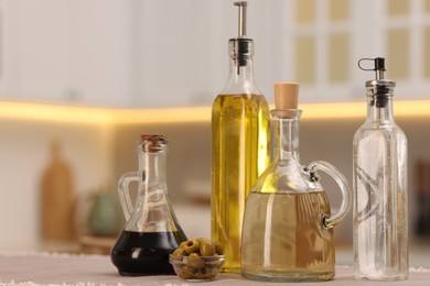 Photo of Bottles of salad dressings and olives on table in kitchen