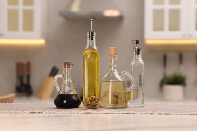 Photo of Bottles of salad dressings and olives on white table in kitchen