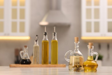 Photo of Bottles of salad dressings and olives on white table in kitchen, space for text