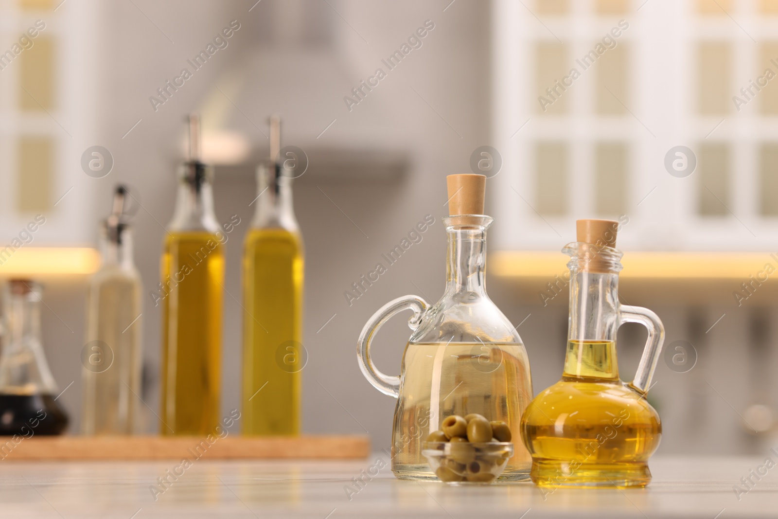 Photo of Bottles of salad dressings and olives on white table in kitchen, space for text