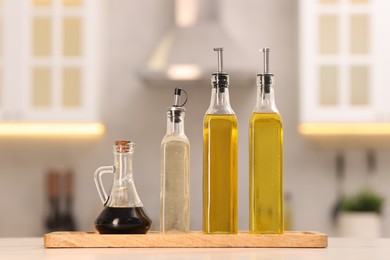 Photo of Bottles of salad dressings on white table in kitchen