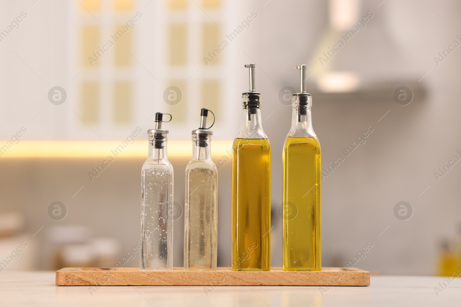 Photo of Bottles of salad dressings on white table in kitchen