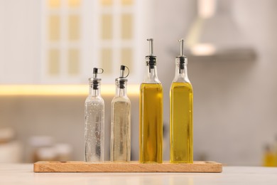 Photo of Bottles of salad dressings on white table in kitchen