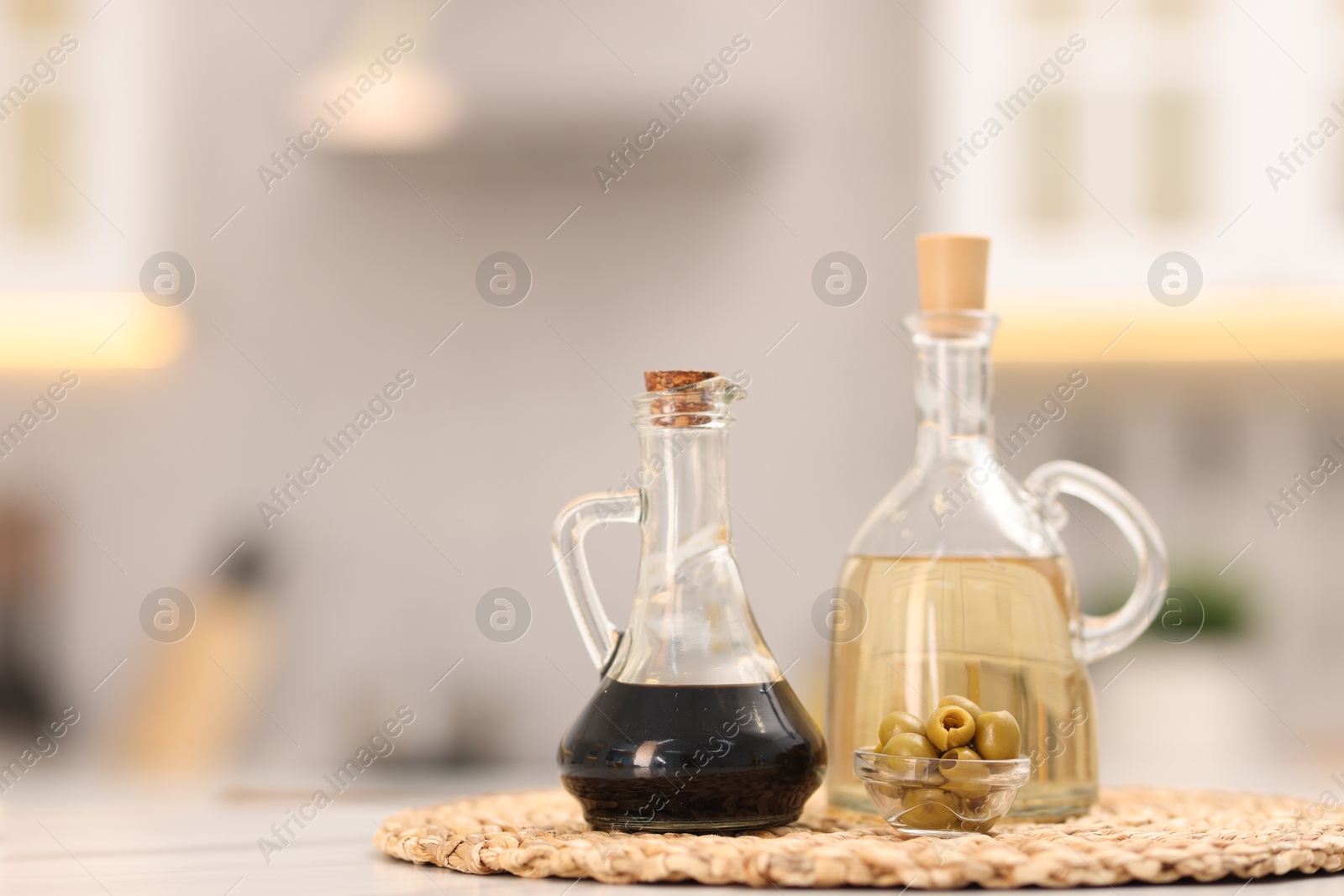 Photo of Bottles of salad dressings and olives on white table in kitchen, space for text