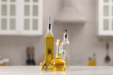 Photo of Bottles of salad dressings and olives on white table in kitchen