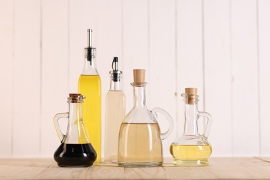 Photo of Bottles of salad dressings on wooden table