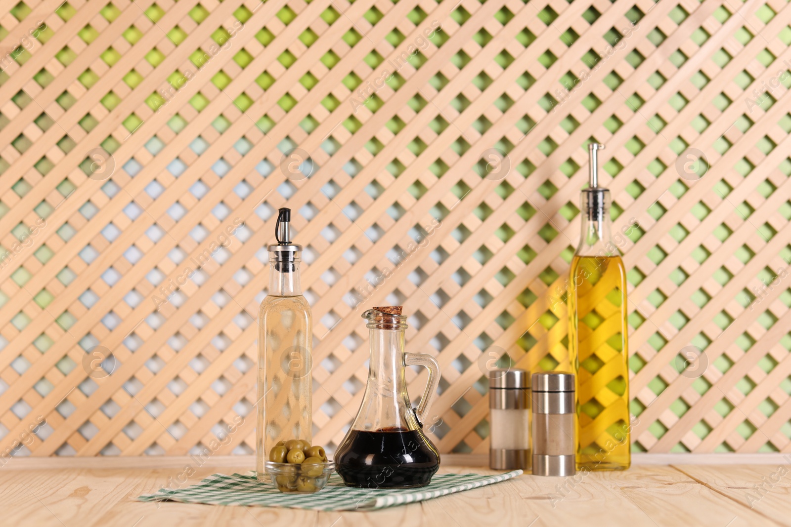 Photo of Bottles of salad dressings, salt, pepper and olives on wooden table