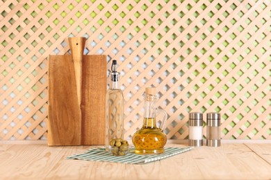 Photo of Bottles of salad dressings, salt, pepper and olives on wooden table