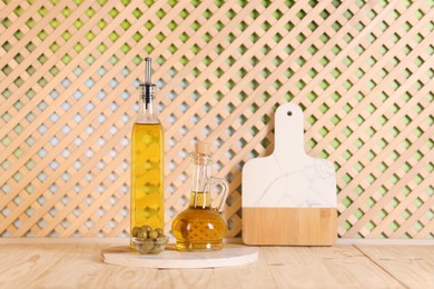 Photo of Bottles of salad dressings and olives on wooden table