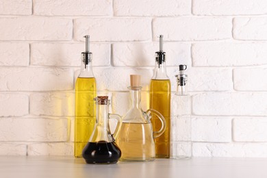 Photo of Bottles of salad dressings on white table near brick wall