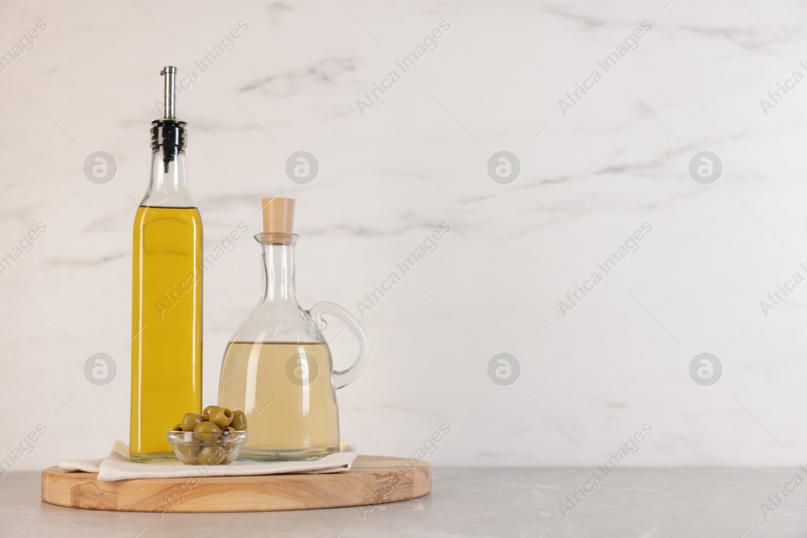 Photo of Bottles of salad dressings and olives on light grey table, space for text