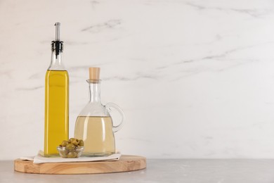 Photo of Bottles of salad dressings and olives on light grey table, space for text