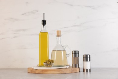 Photo of Bottles of salad dressings, salt, pepper and olives on light grey table