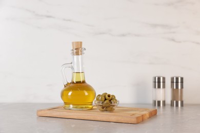 Photo of Bottle of oil, salt, pepper and olives on light grey table