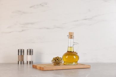 Photo of Bottle of oil, salt, pepper and olives on light grey table