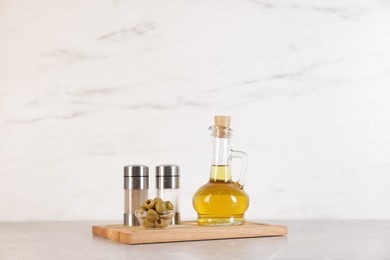 Photo of Bottle of oil, salt, pepper and olives on light grey table