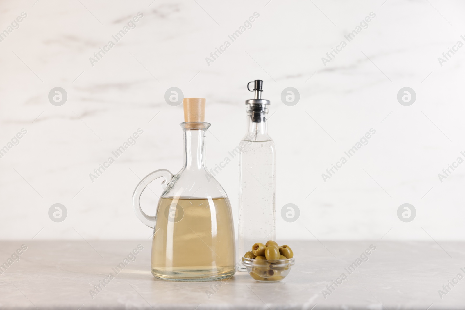 Photo of Bottles of salad dressings and olives on light grey table