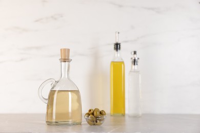 Photo of Bottles of salad dressings and olives on light grey table