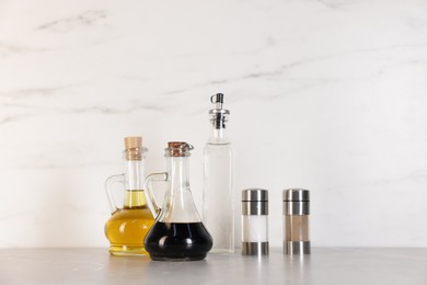 Photo of Bottles of salad dressings, salt and pepper on light grey table