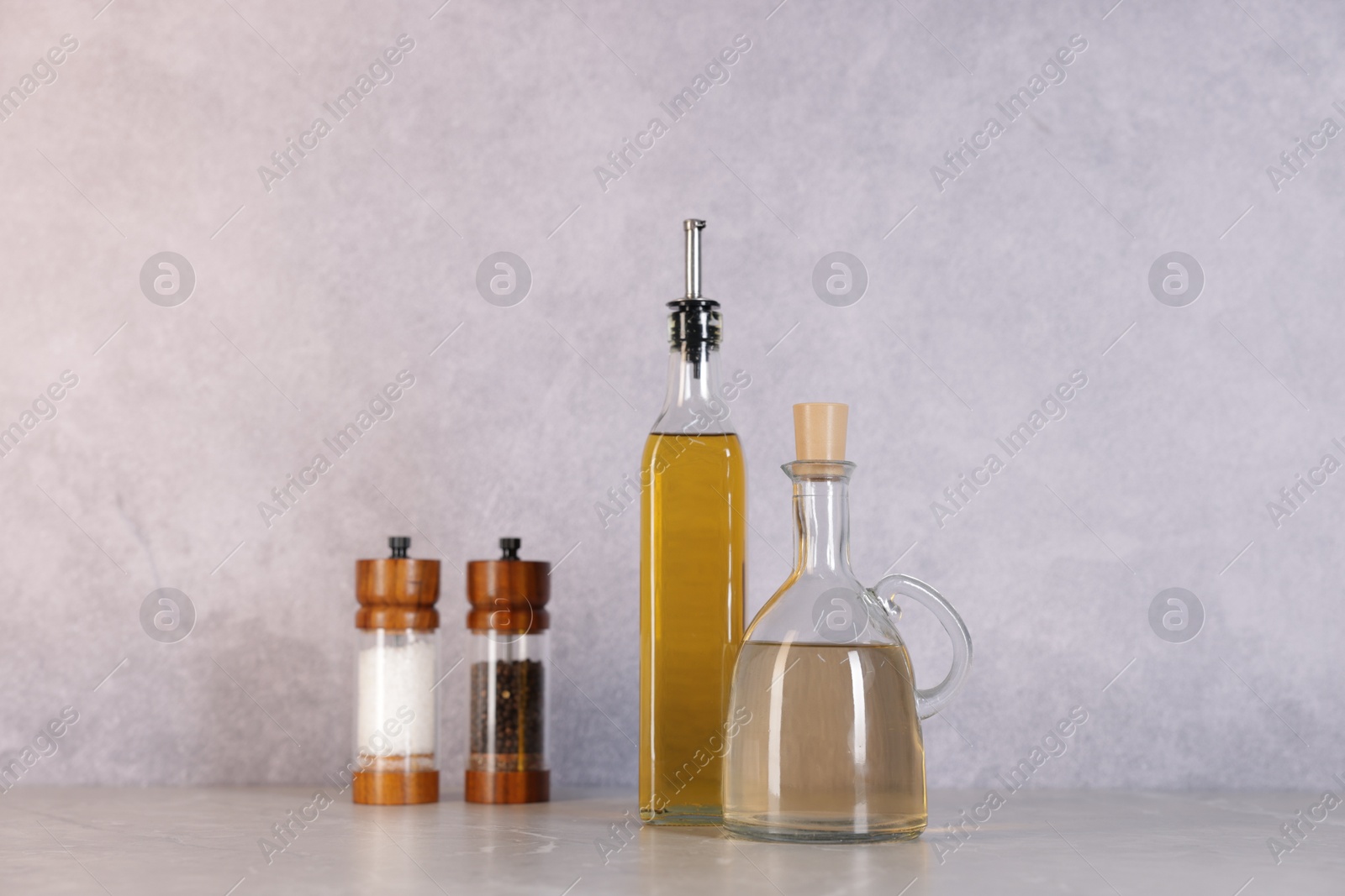 Photo of Bottles of salad dressings, salt and pepper on light grey table