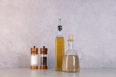 Photo of Bottles of salad dressings, salt and pepper on light grey table