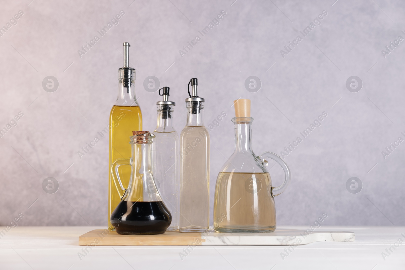 Photo of Bottles of salad dressings on white wooden table