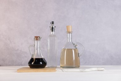 Photo of Bottles of salad dressings on white wooden table