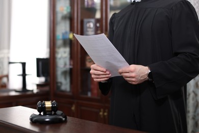 Photo of Judge with document at table in courtroom, closeup