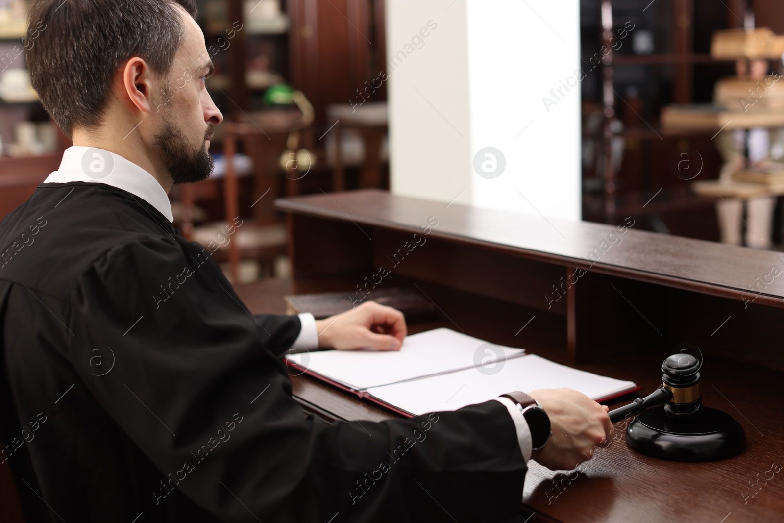 Photo of Judge striking gavel at wooden table in courtroom