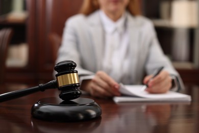 Photo of Judge working with documents at table in office, focus on gavel