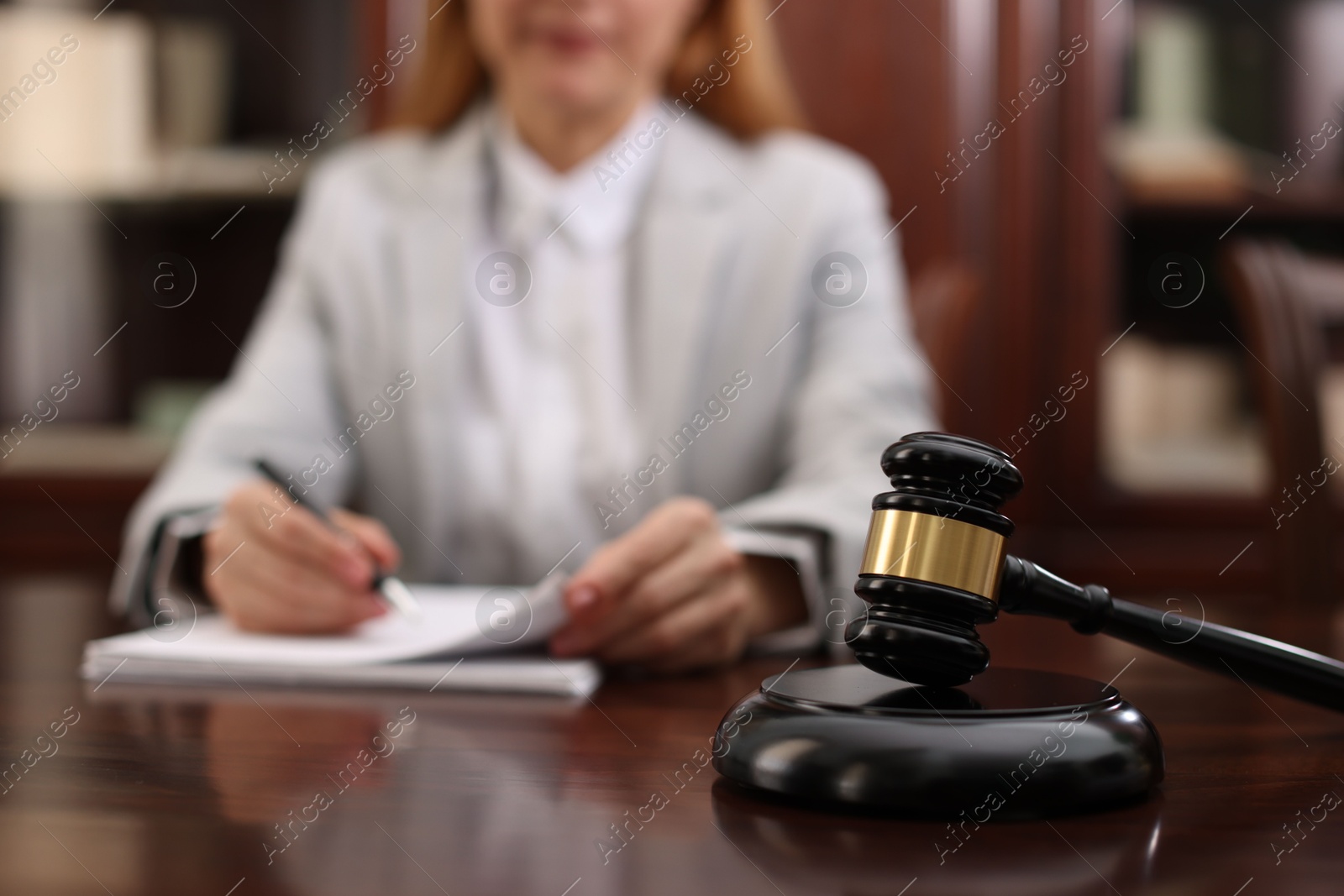 Photo of Judge working with documents at table in office, focus on gavel