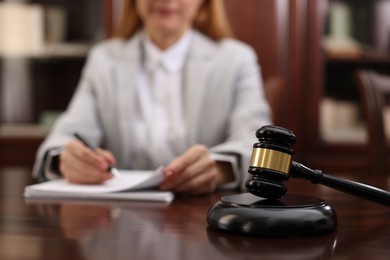 Photo of Judge working with documents at table in office, focus on gavel