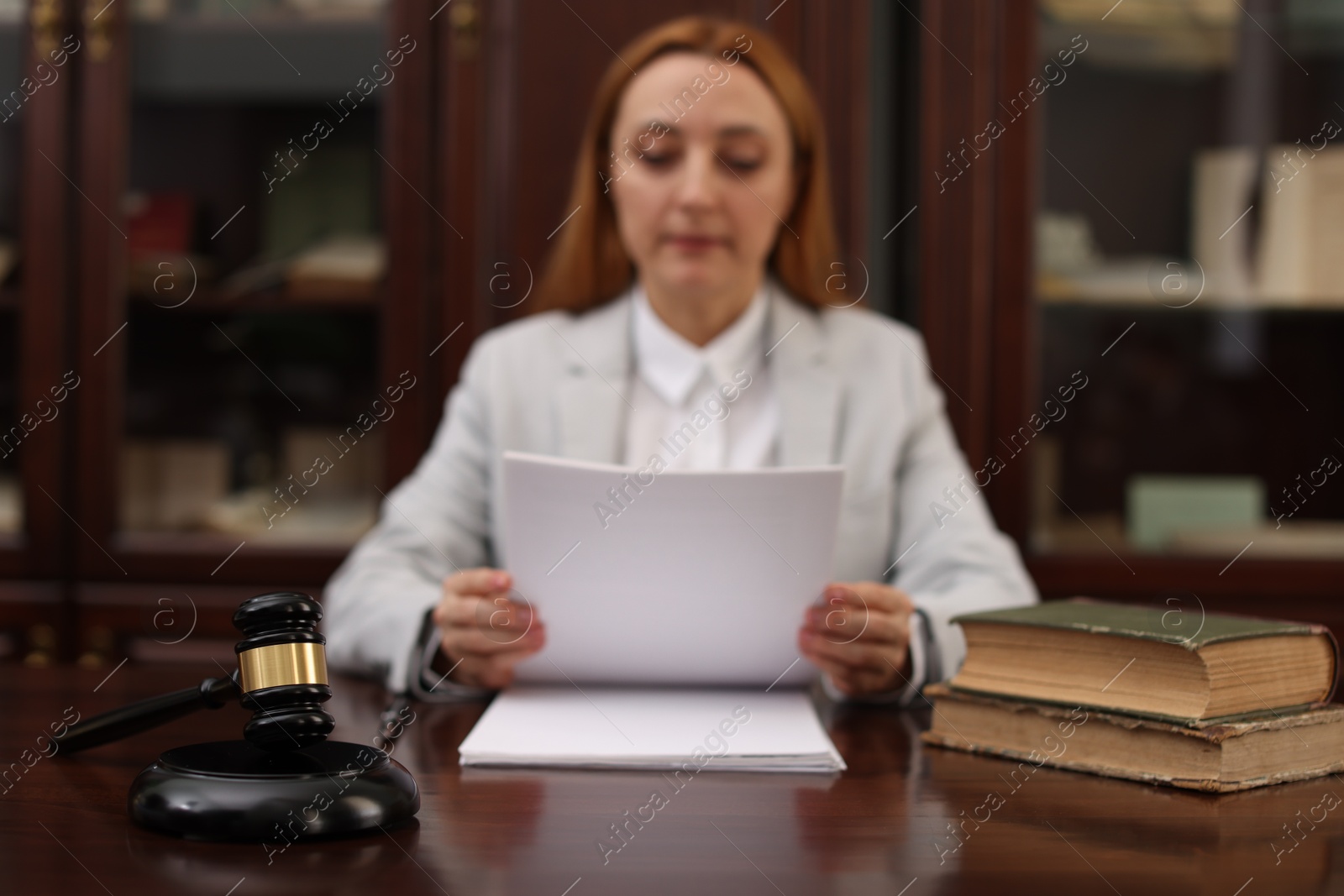 Photo of Judge working with documents at wooden table in office, focus on gavel