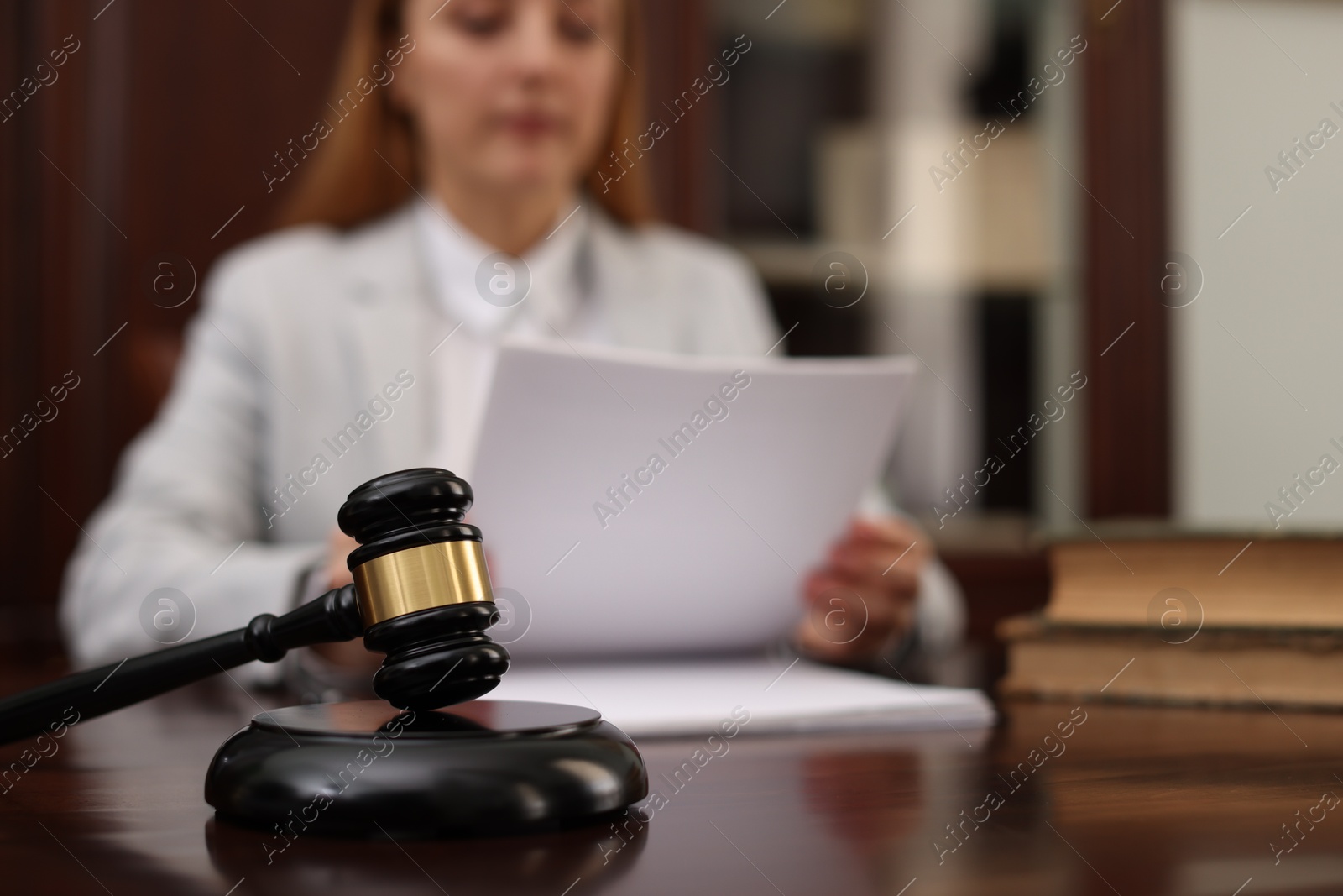 Photo of Judge working with documents at wooden table in office, focus on gavel