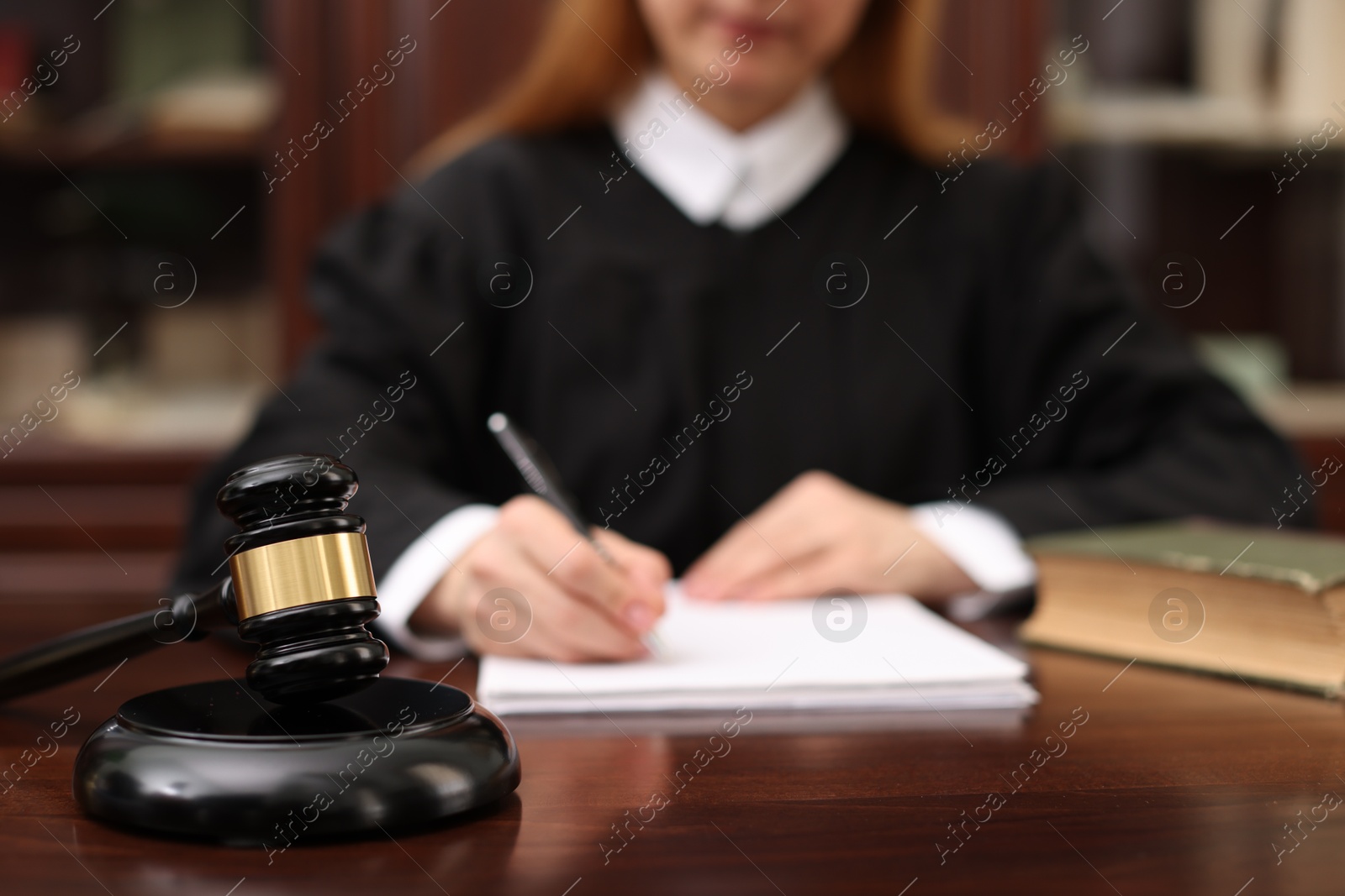 Photo of Judge working with documents at table in office, focus on gavel