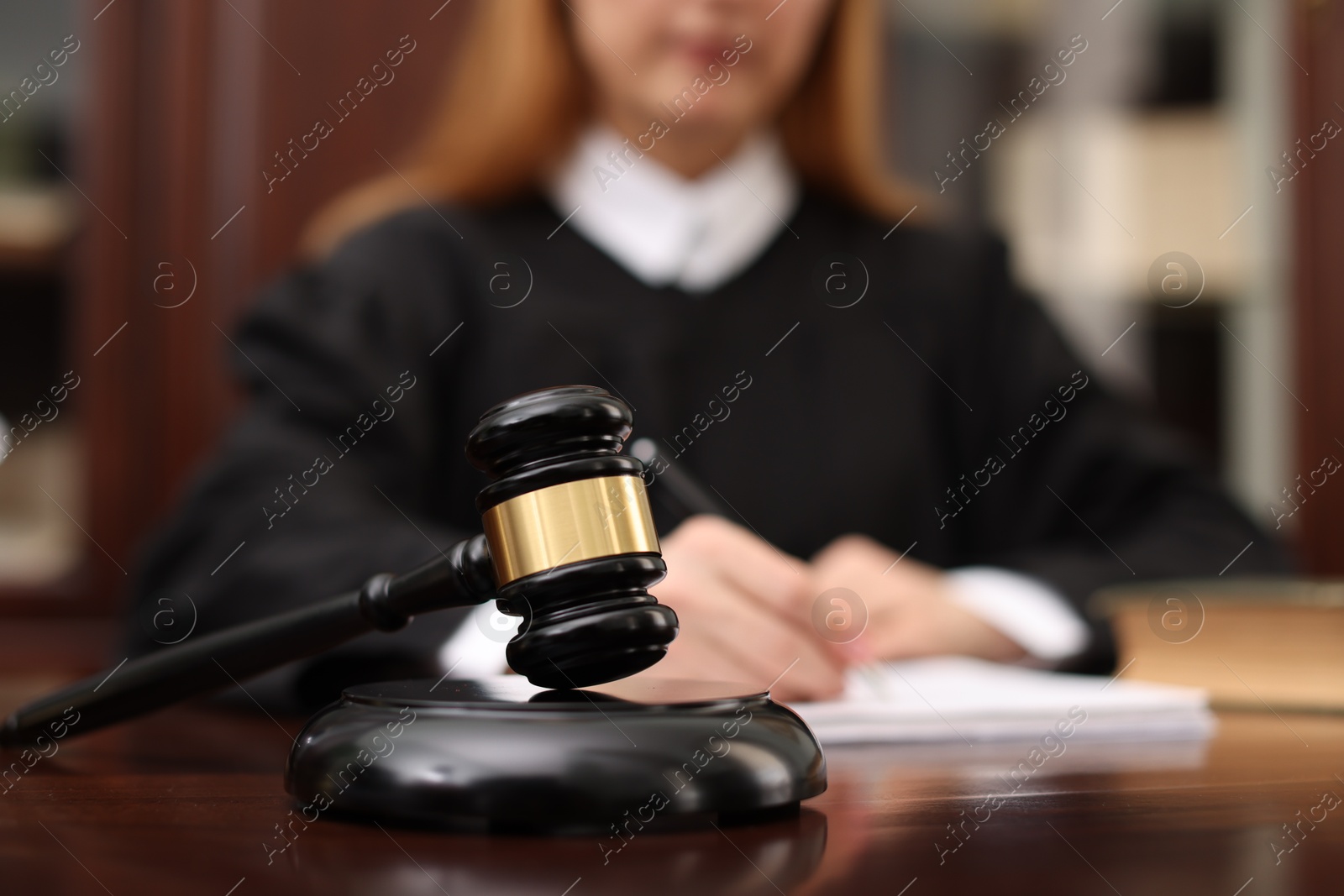 Photo of Judge working with documents at table in office, focus on gavel