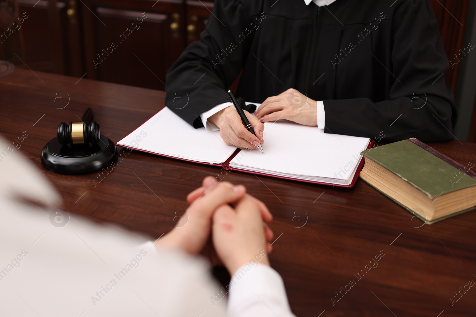 Photo of Judge working with documents at wooden table in office, closeup