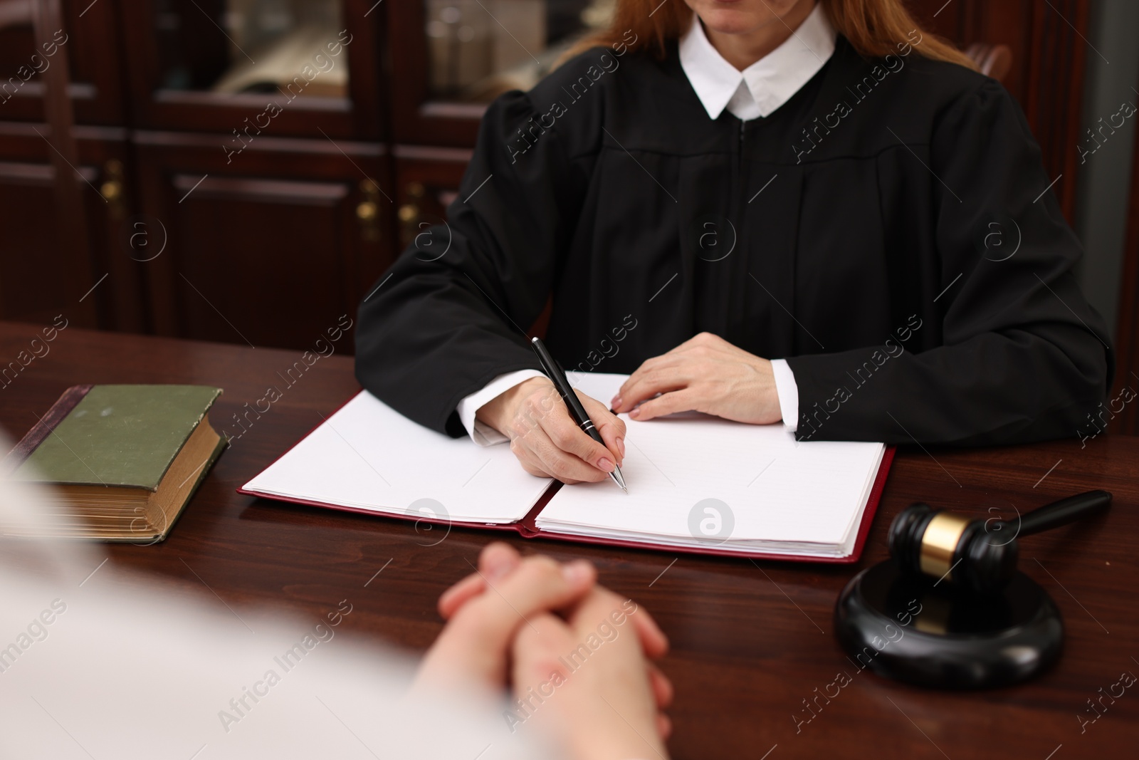 Photo of Judge working with documents at wooden table in office, closeup