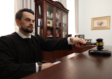 Photo of Judge striking gavel at wooden table in courtroom