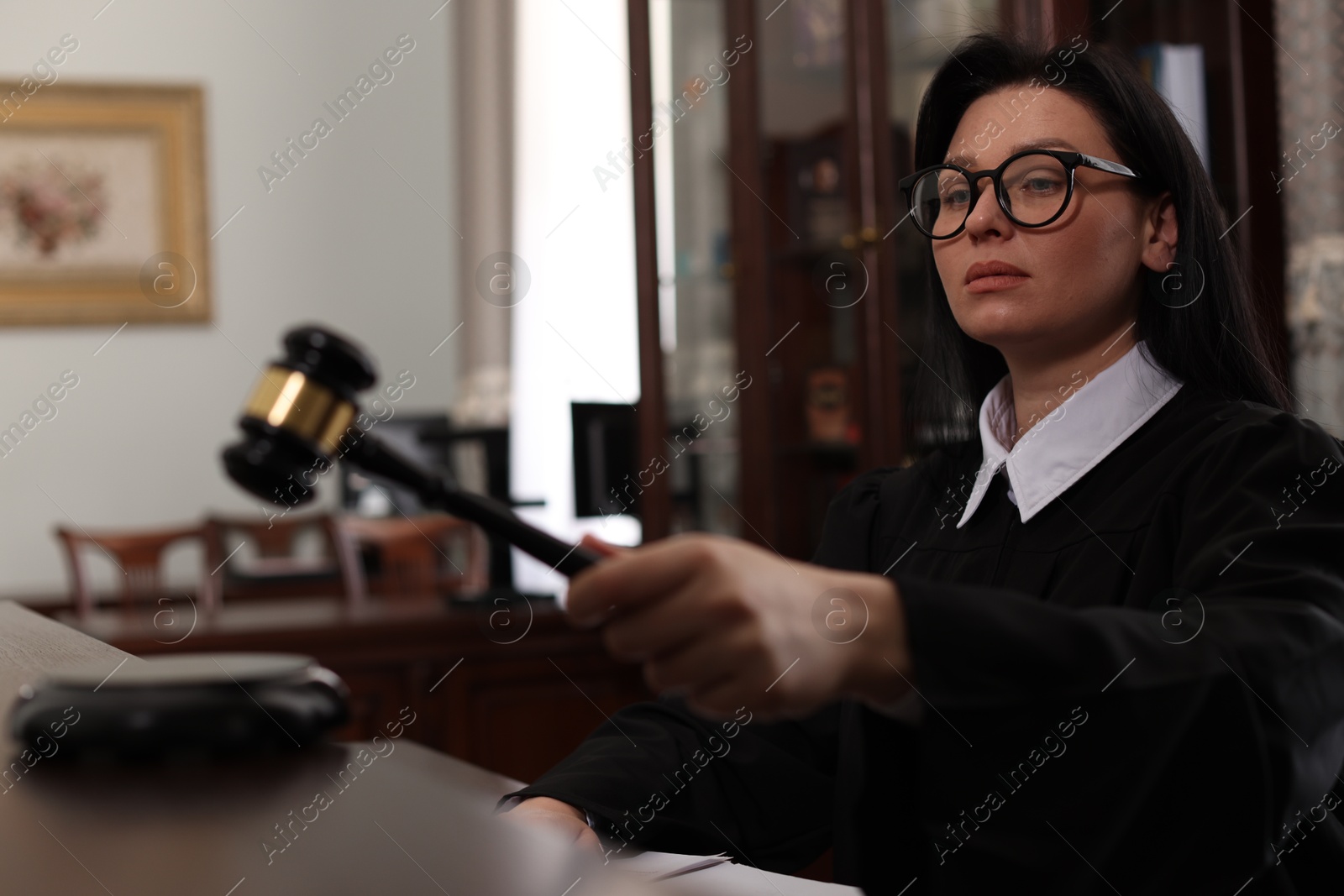 Photo of Judge striking gavel at table in courtroom