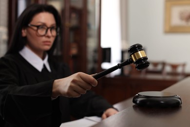 Photo of Judge striking gavel at table in courtroom, selective focus