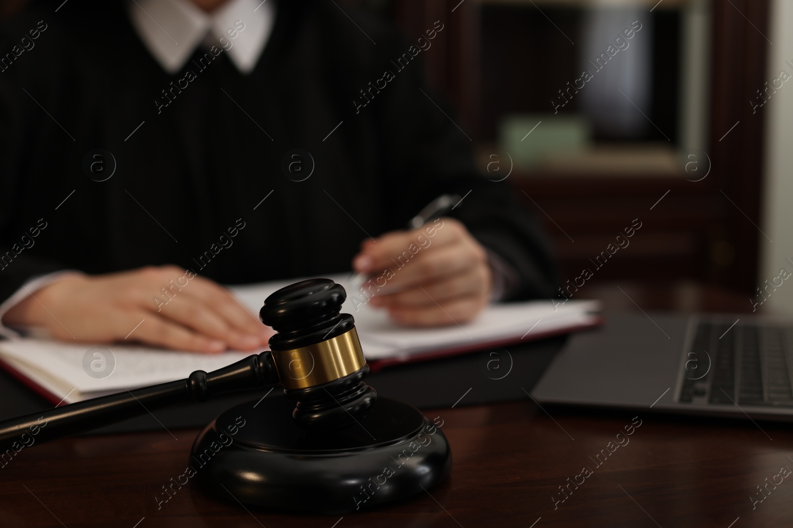 Photo of Judge working at wooden table in office, focus on gavel