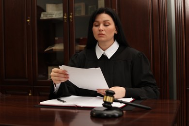 Photo of Judge working with documents at wooden table in office