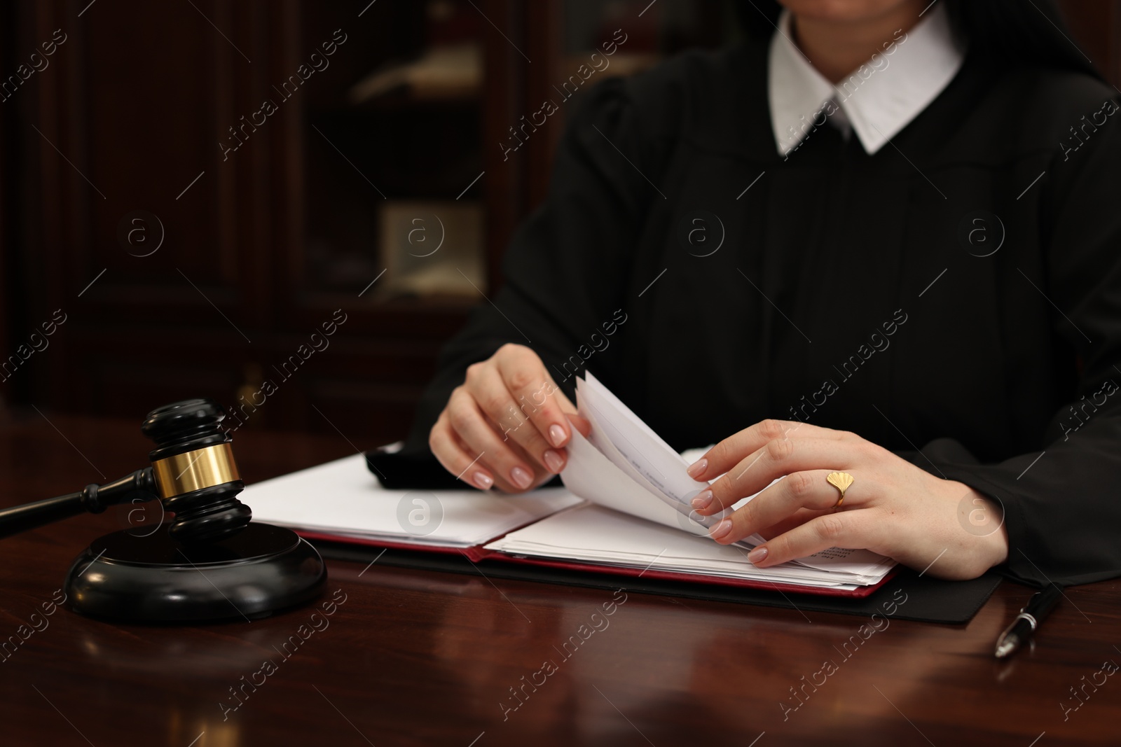 Photo of Judge working with documents at wooden table in office, closeup