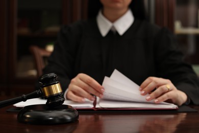 Photo of Judge working with documents at wooden table in office, closeup